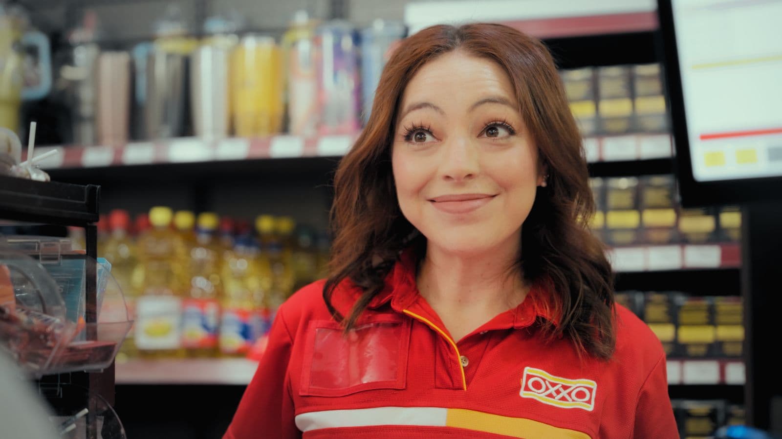 Empleada de OXXO sonriendo detrás del mostrador en el comercial de Helados Gonfra