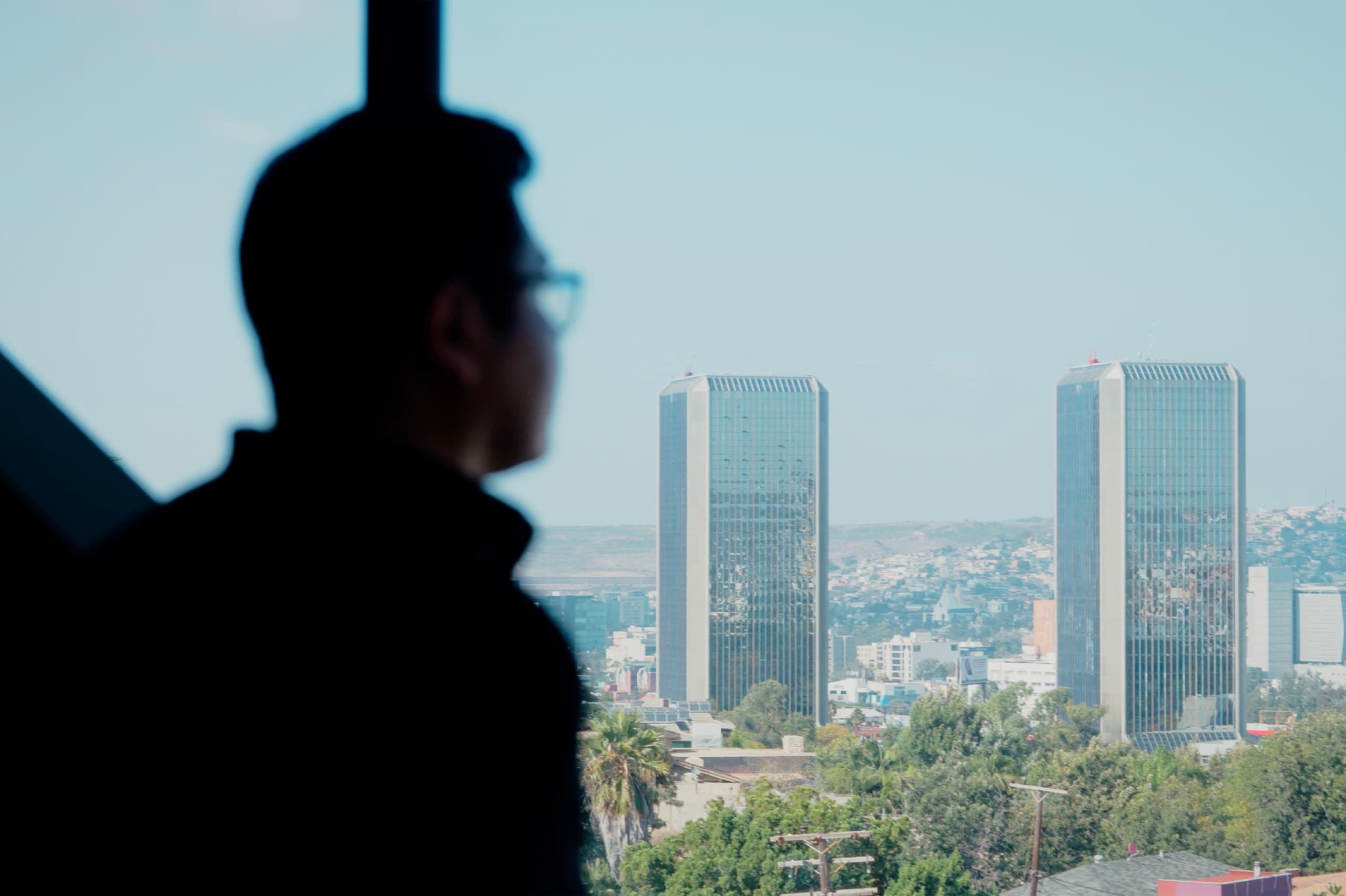 Ejecutivo frente a la ventana de una oficina con vista a las torres de Tijuana