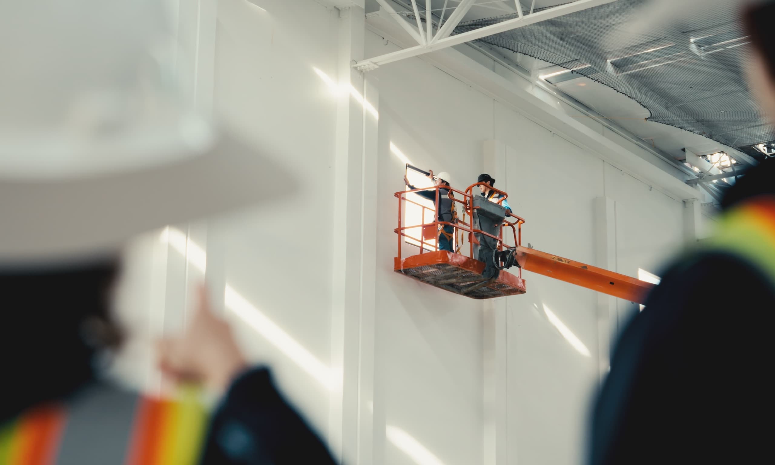 Trabajadores en plataforma elevadora dentro de una nave industrial