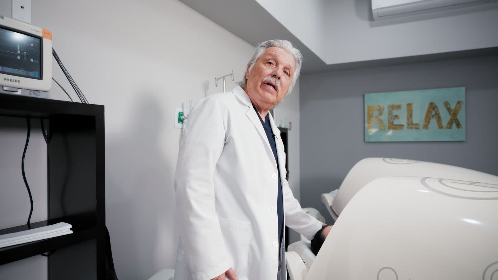 Médico explicando un tratamiento en un consultorio con equipo de monitoreo